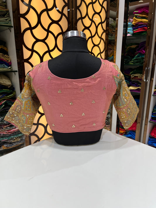 Elegant peach-pink designer blouse with a flattering deep V-neck and subtle golden butti work. Features beautifully embroidered statement sleeves for a rich, festive look—perfect for weddings and special occasions.